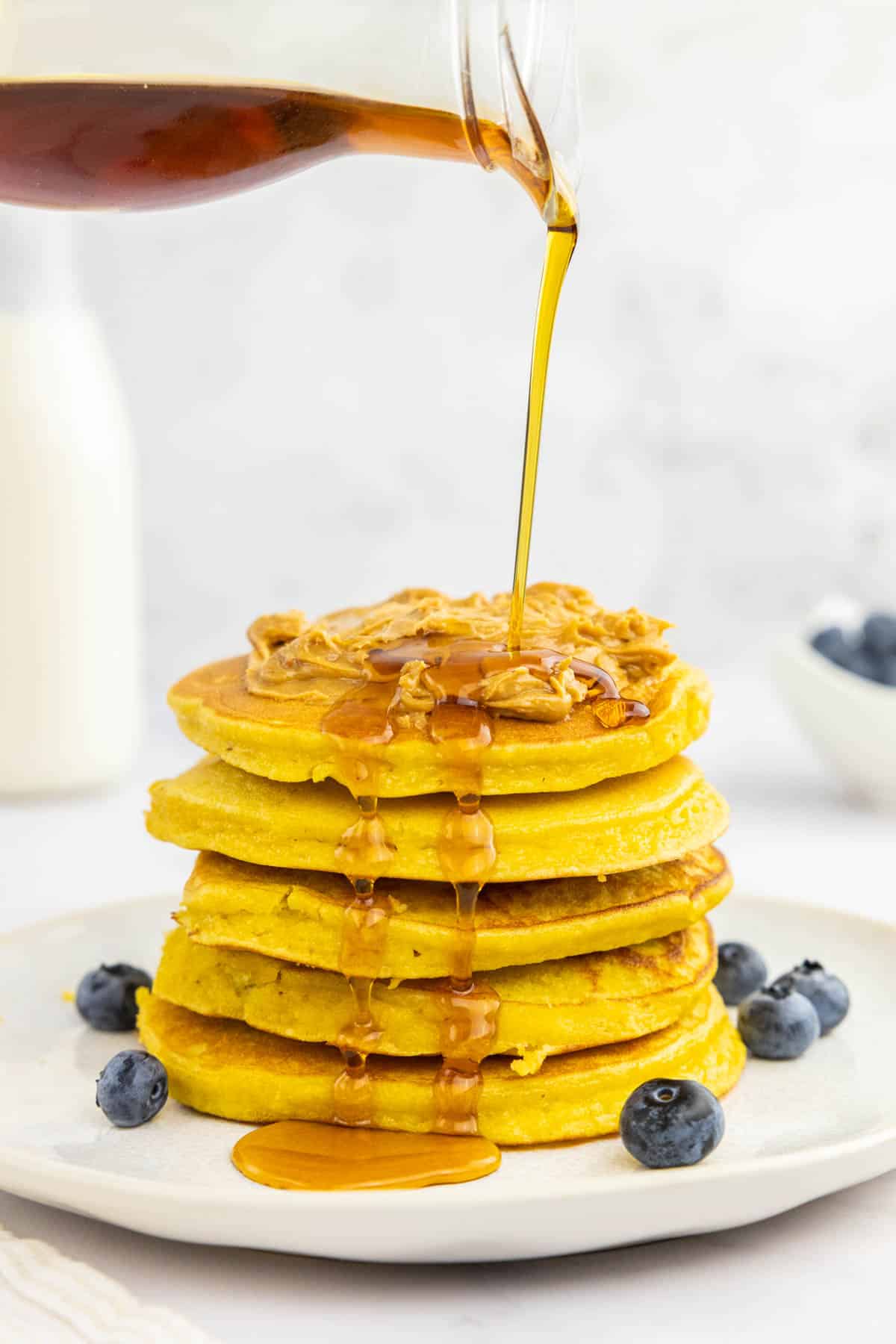 Pouring maple syrup over the protein pancakes