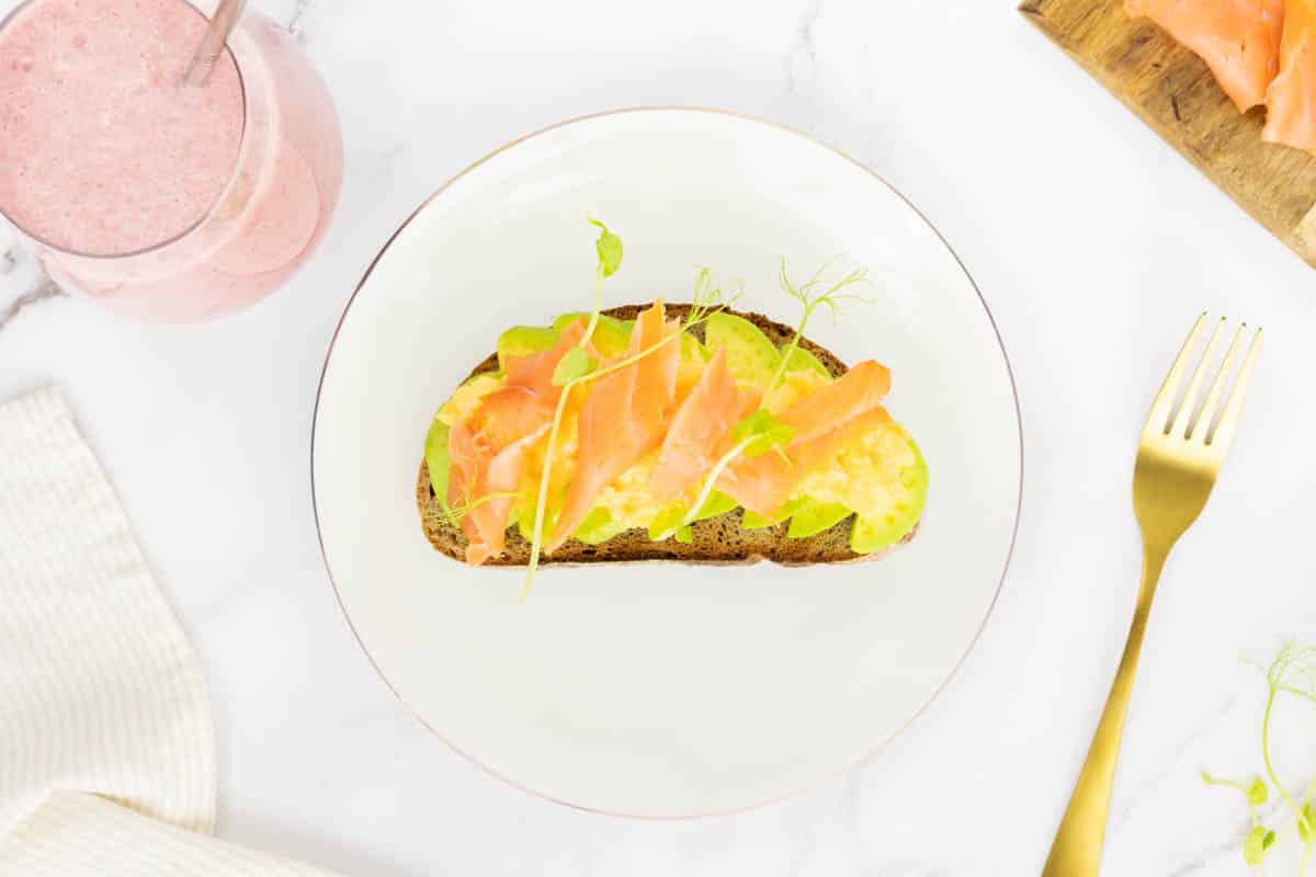 High calorie breakfast of avocado, eggs, smoked salmon and wholegrain toast with a fruit smoothie