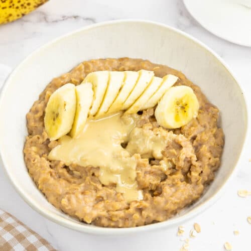 High calorie oatmeal in a bowl topped with banana and nut butter.