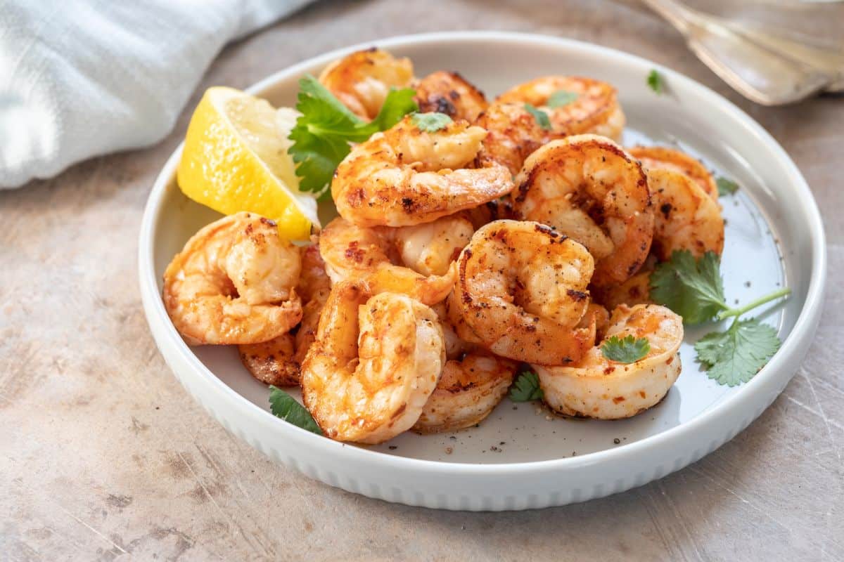 20 Highest Protein Fish and Seafood 8 A plate of cooked shrimp with herbs.