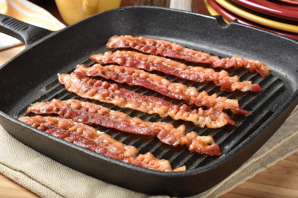20 Highest Calorie Meats for Weight Gain 4 Bacon being cooked on a griddle.