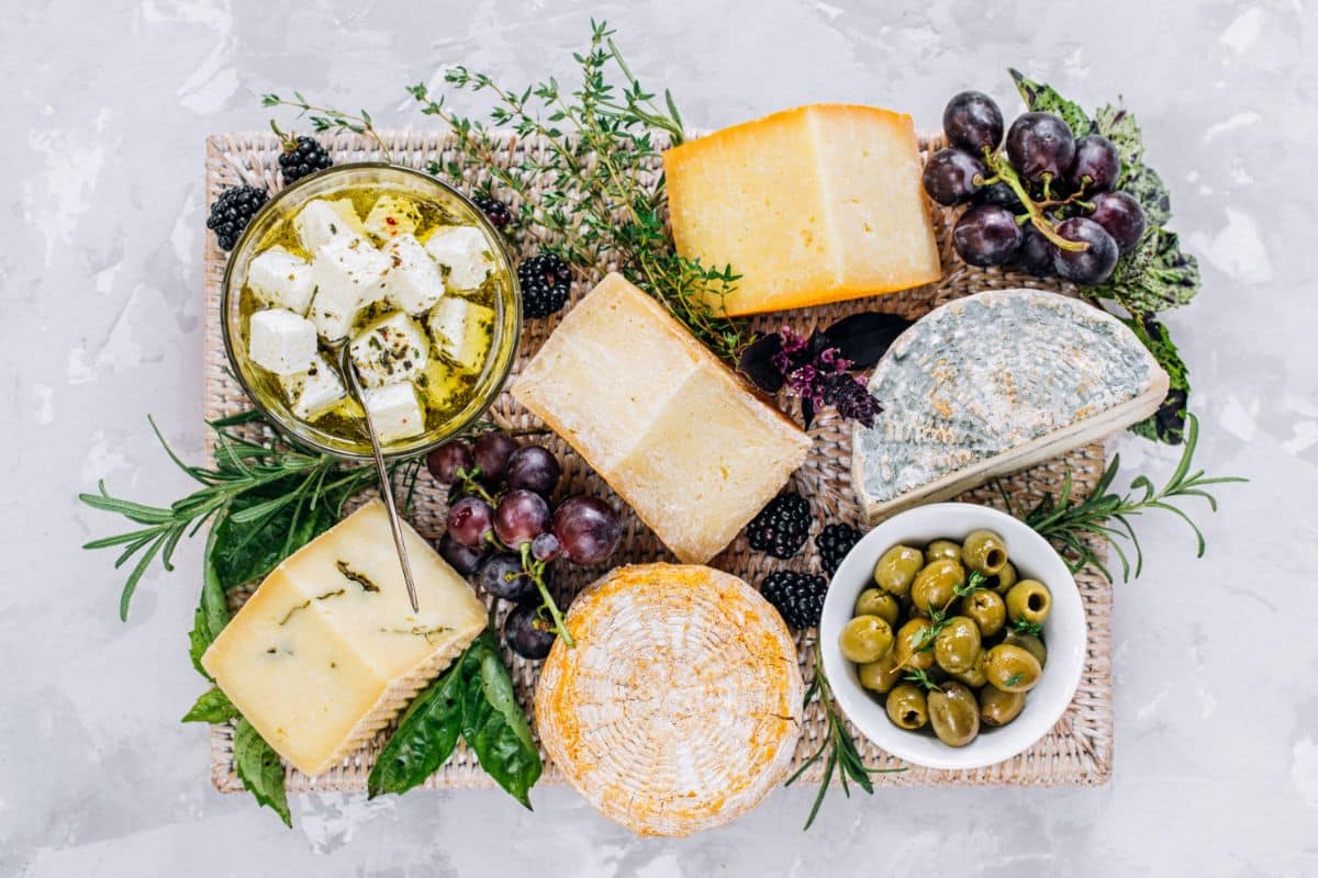 Cheese board on a counter next to olives.