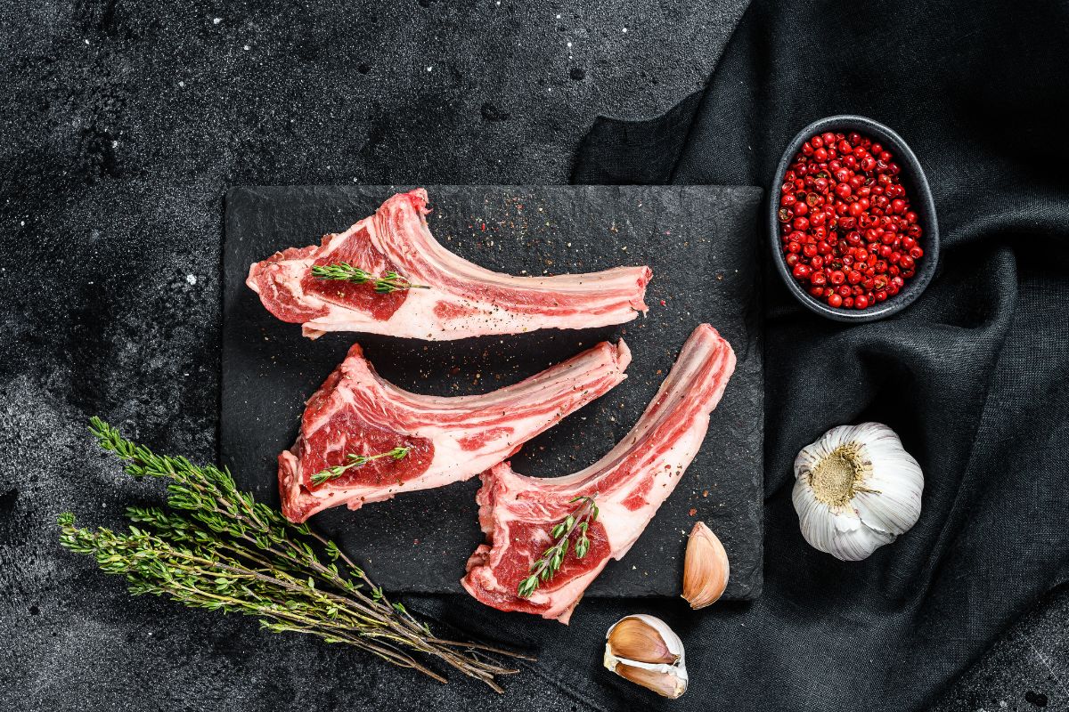 20 Highest Calorie Meats for Weight Gain 10 Lamb chops on a board with herbs and garlic.