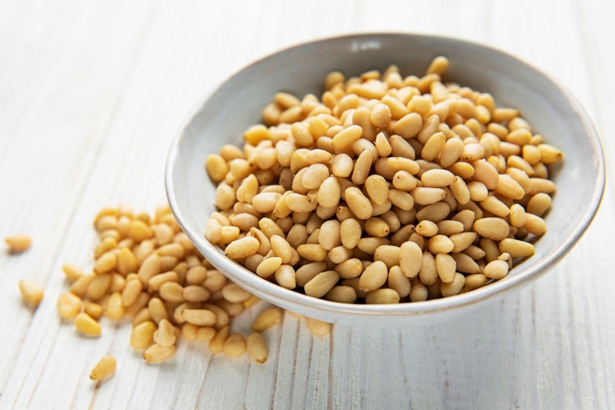The Top 10 Highest Protein Nuts 9 Pine nuts in a bowl on a wooden table.