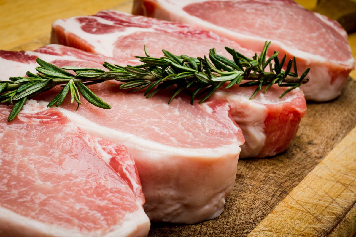 Pork chops on a wooden board with rosemary.