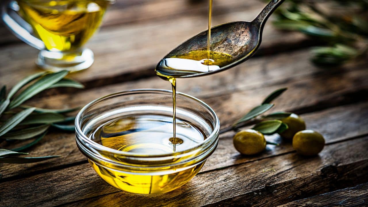 10 Common Foods That Are Secretly High in Calories 8 Olive oil being poured on a tablespoon